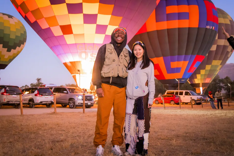 Couple posing together before glowing balloons at sunrise in the launch field