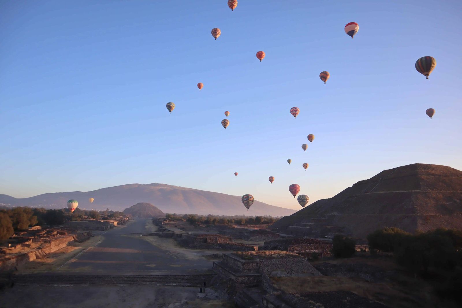 Decenas de globos aerostáticos sobre la Calzada de los Muertos y la Pirámide del Sol al amanecer en Teotihuacán